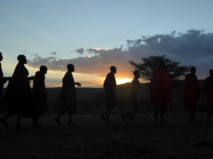 A group of Maasai Men is dancing in the sunset