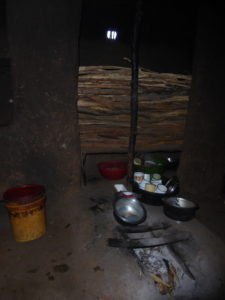 Inside a Maasai house: the kitchen with a fireplace and many cups and pots.