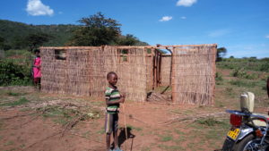 A new Maasai house is being build. The women in the back are working on the scaffolding out of branches.