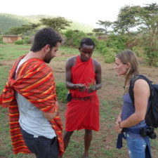 On a walking safari a Maasai guide is explaining different herbs to two visitors.