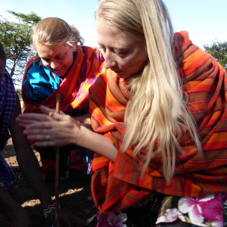 Two european women try to make fire the Maasai way - with two sticks.