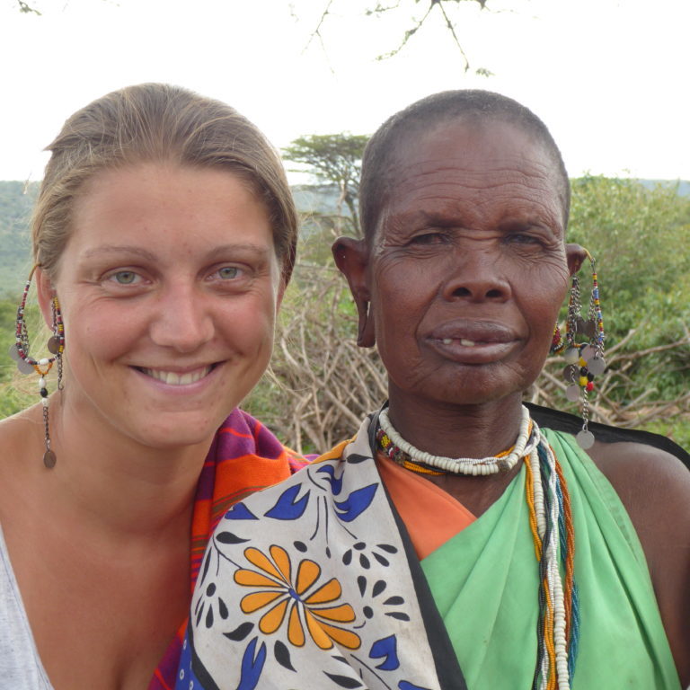 A european and a maasai woman share a pair of Maasai earrings out of beads.